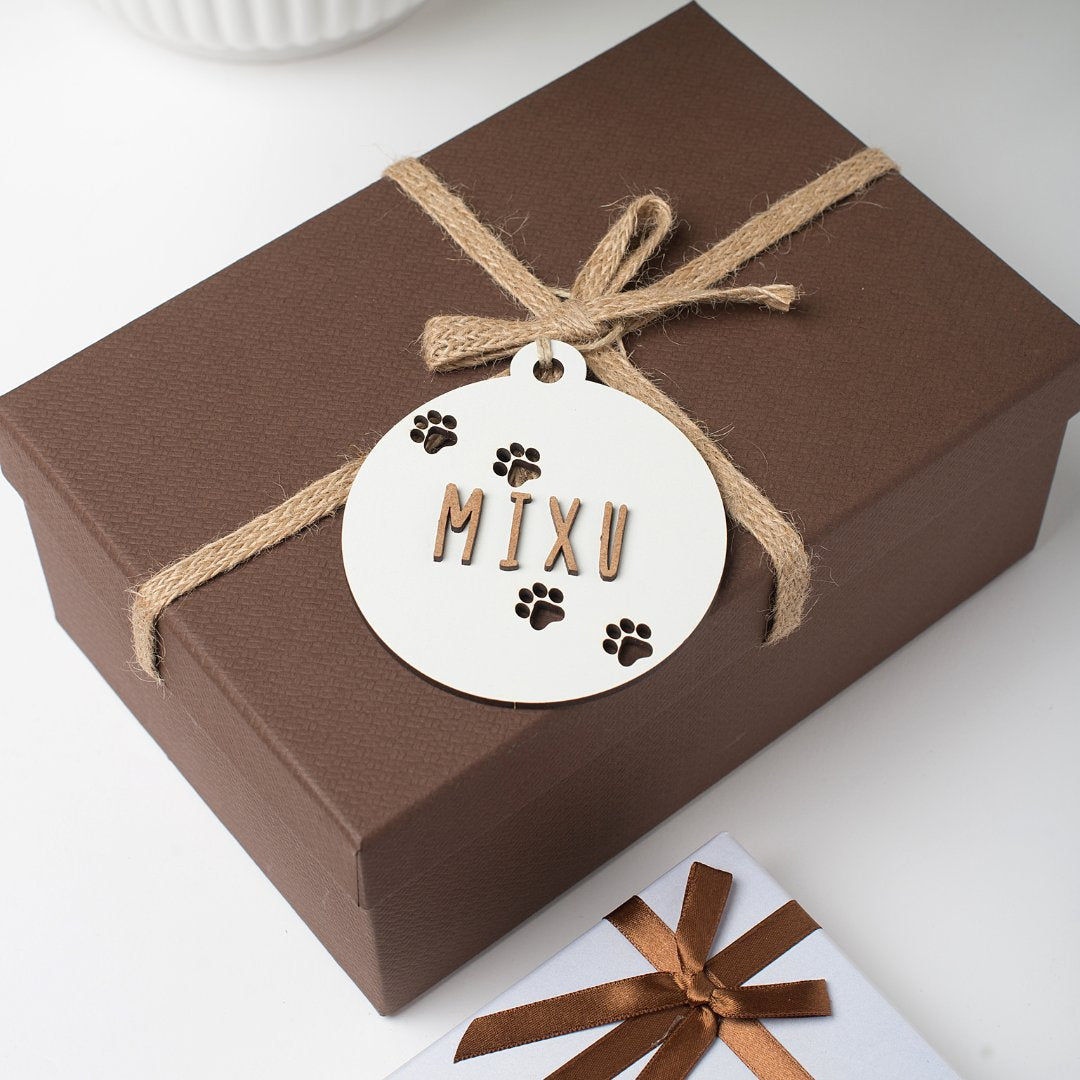 Bolas de Navidad blanca con huellas y nombre colgadas en paquete